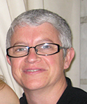 woman with very short white hair, black glasses