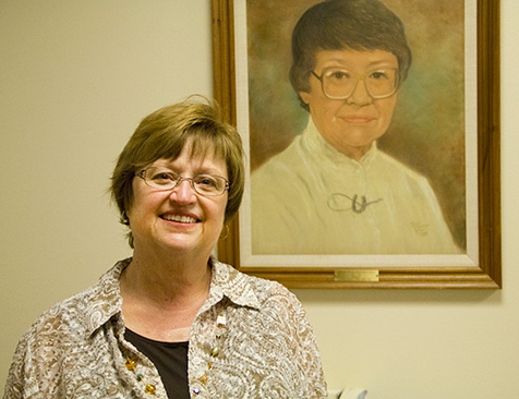 Nancy Dzieken stands in front of her Aunt Dorothy Tupper's picture in the UW School of Nursing
