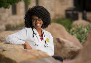 A graduate from the University of Wyoming Fay W. Whitney School of Nursing poses in a lab coat on the UW campus.