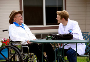 A medical professional and patient sit outside and laugh together.