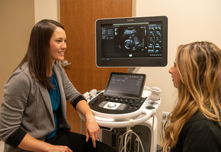 A doctor has a consult with a patient in a medical exam room.