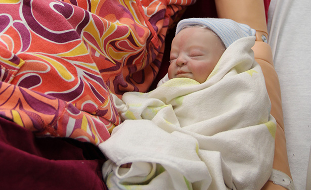 Seemingly real baby bundled in simulation mother's arms