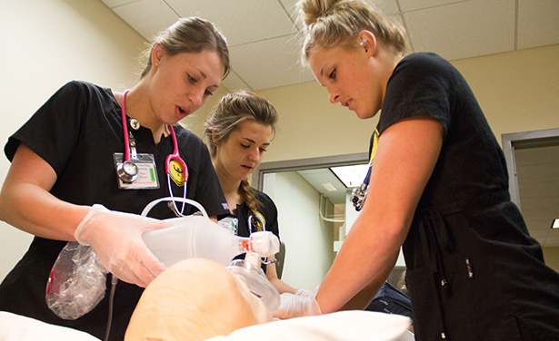 Three students work to get simulated patient breathing.