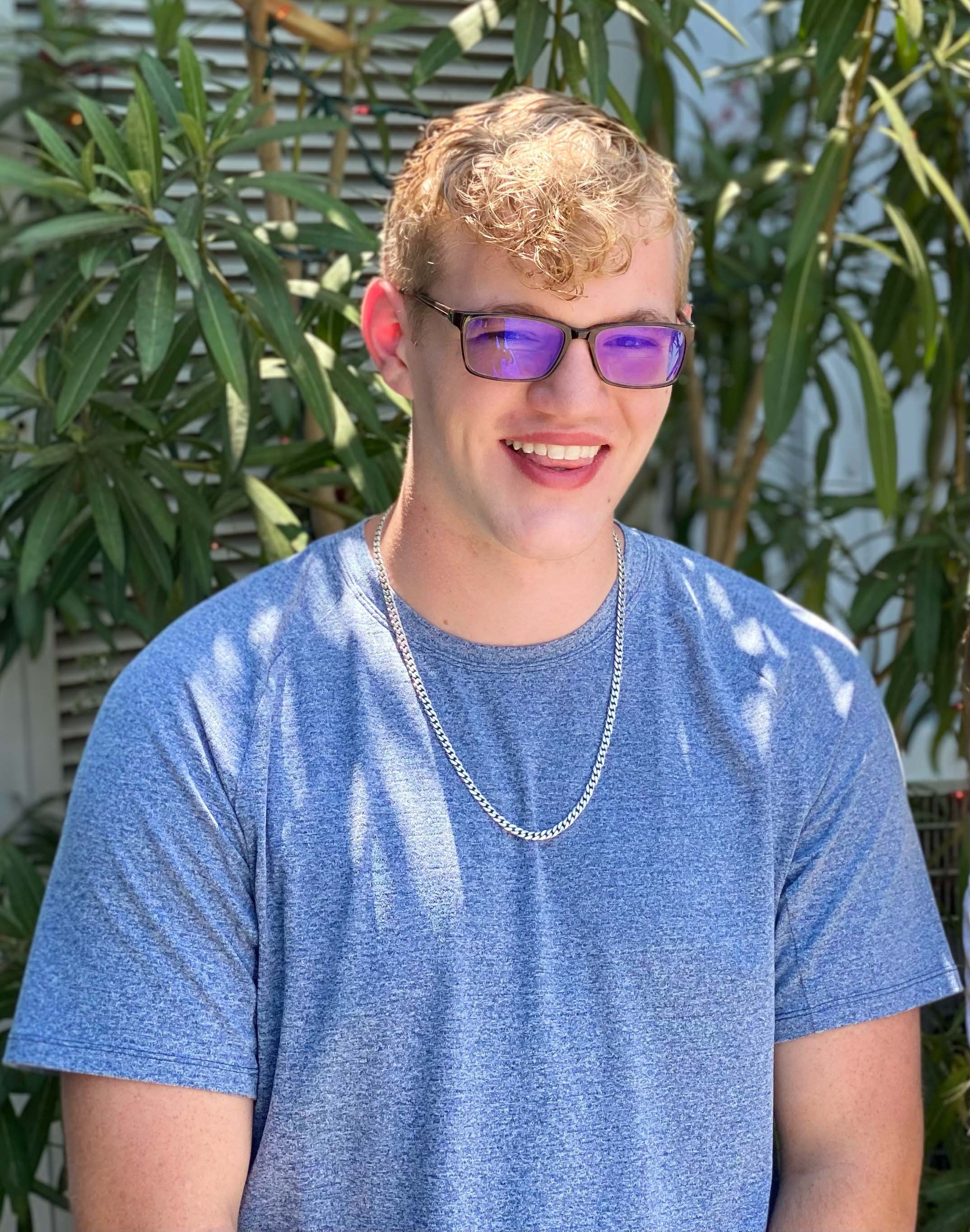 Male student standing outdoors in a garden setting.