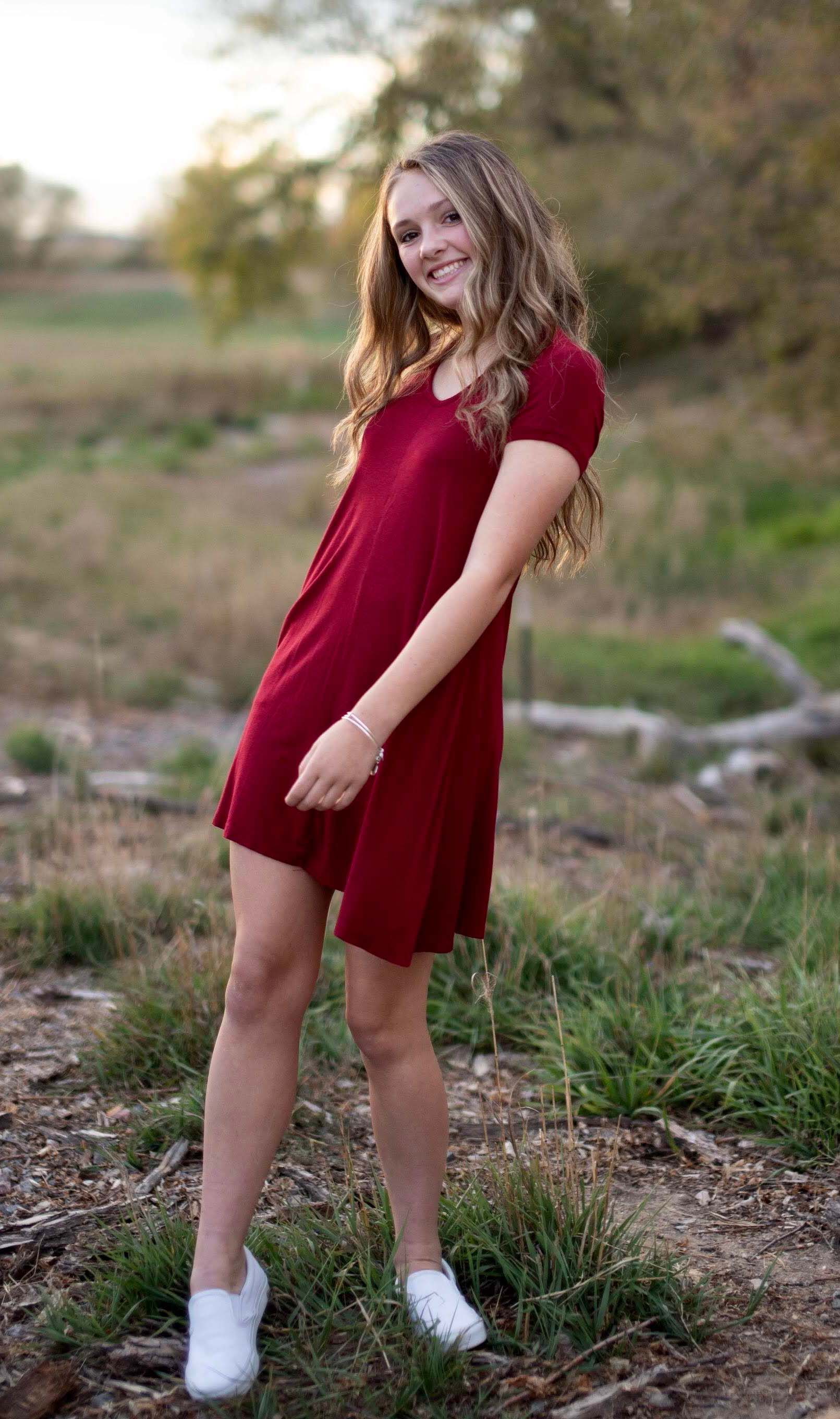 Female student standing outdoors in a red dress.