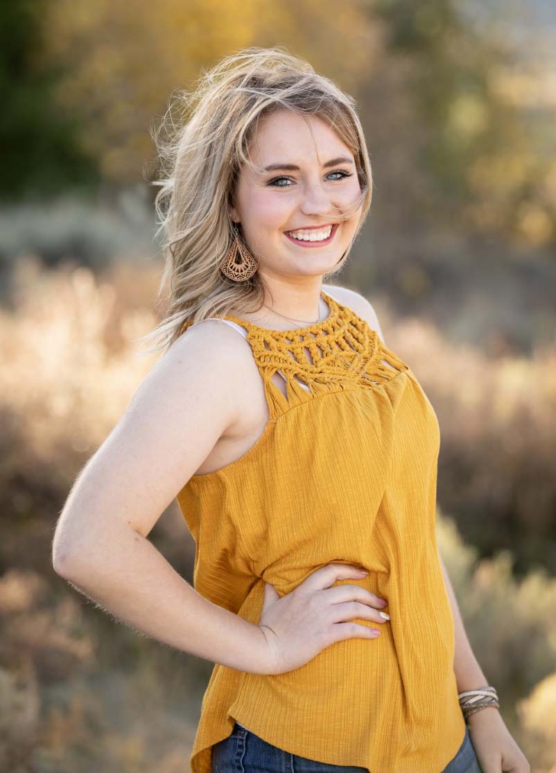 Female student standing outside wearing gold colored shirt.