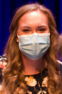 Young woman with long brownish-blonde wavy hair and blue face mask