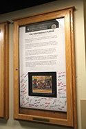pledge signed by students hanging in an enclosed glass case in the school hallway