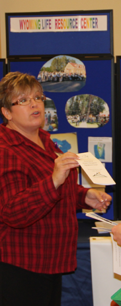 woman with short hair and glasses shares brochure with student