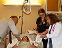 a doctor, a nurse, and nurse manager surround patient in bed