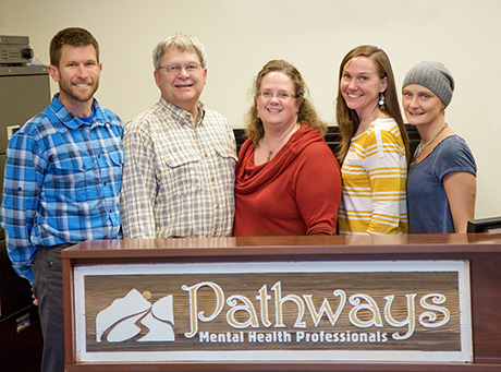 five individuals smile for camera behind Pathways sign