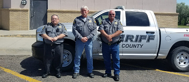 three officers pose in front of the Sheriff's truck