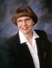business woman in blazer and white blouse, short brown hair and glasses