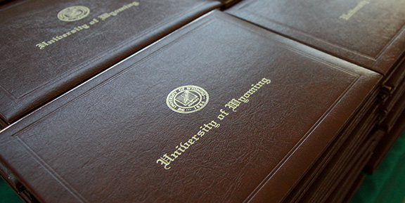 Stacks of brown diploma cases with gold University of Wyoming imprint