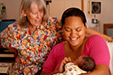 Picture of Brigid Mulloy working as a midwife with a mother and her baby in Hawaii