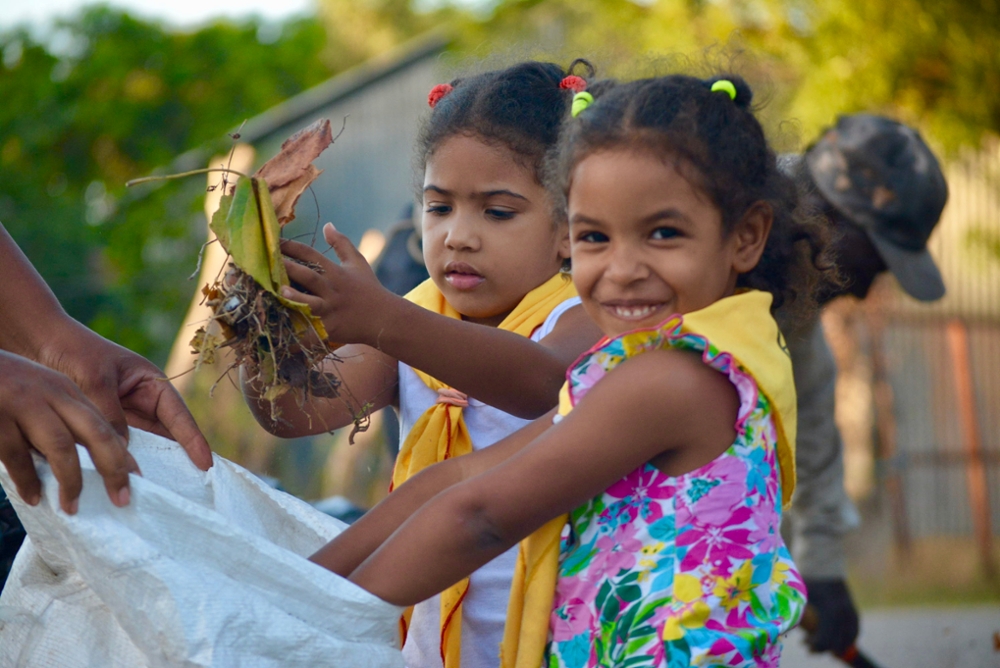 two young girls picking up leaves in the peace corps program