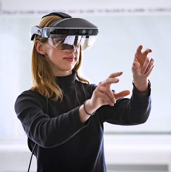Student wearing a virtual reality headset with her hands up 