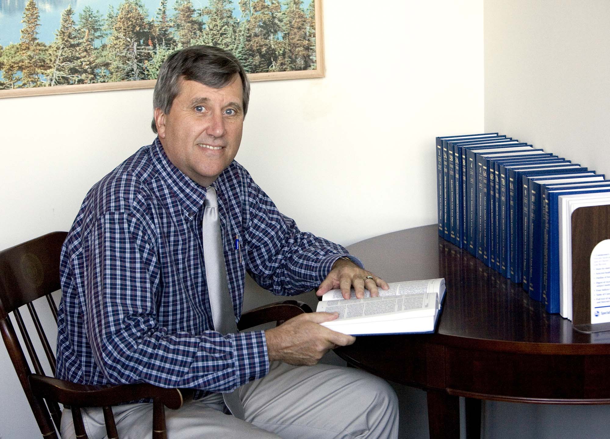 Man setting at a desk reading a book.