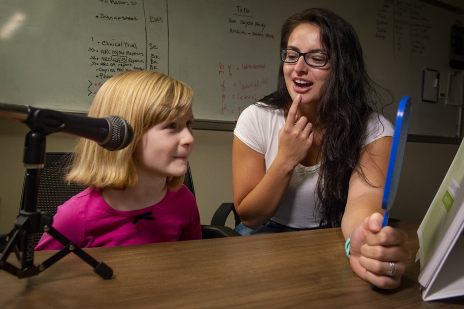 child receiving speech therapy with a mirror