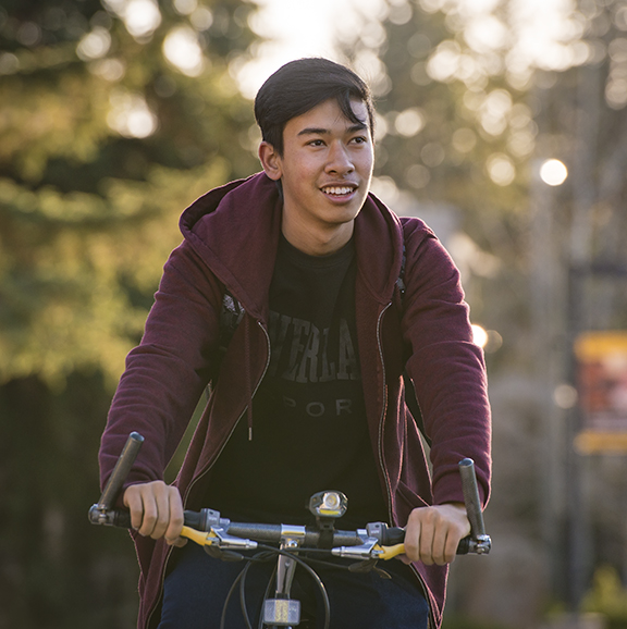 Male student riding a bike on prexy's pasture