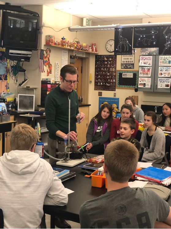 Dr. Hill showing students how different metal compounds burn different colors in a flame