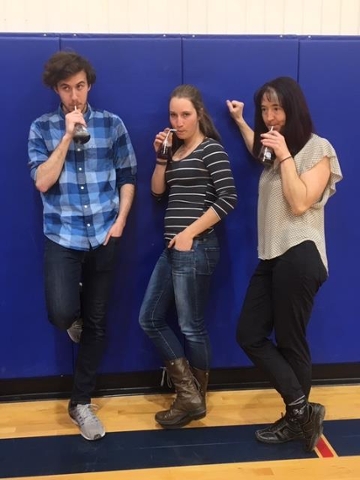 Tyler, Ella, and Rachel blow bubbles through a straw into erlenmeyer flask