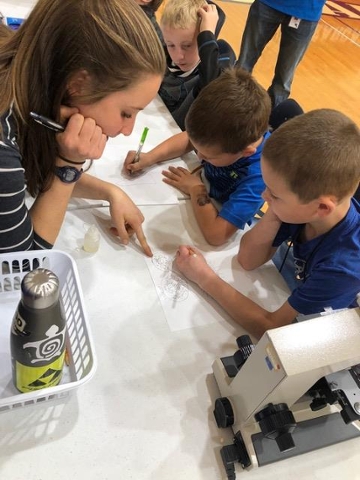 Ella helps a student draw a bacterium