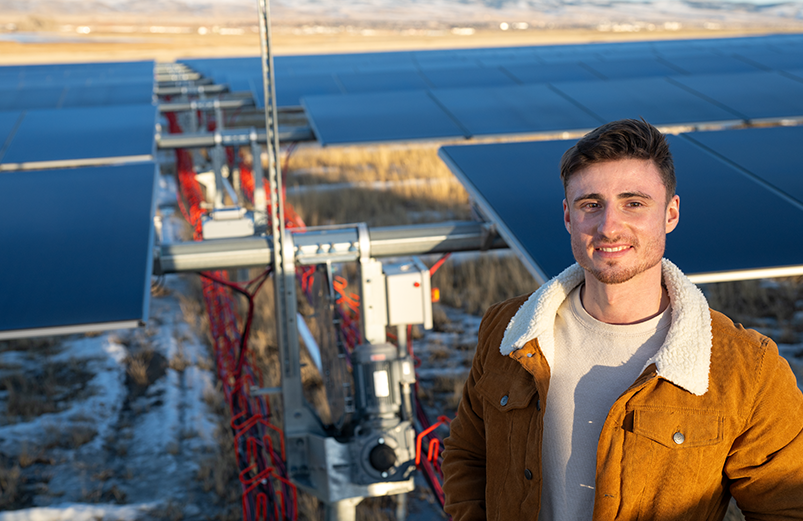 guy standing in front of solar panels in a field