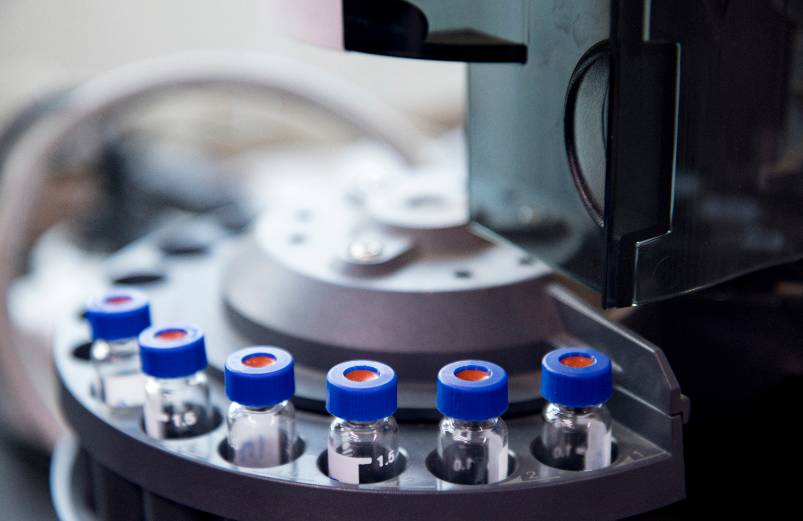 Water samples loaded into small glass vials with blue lids, loaded into an autosampler.