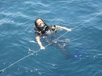 Thao Nguyen, wearing a scuba suit, floats in clear water while holding an anchor line