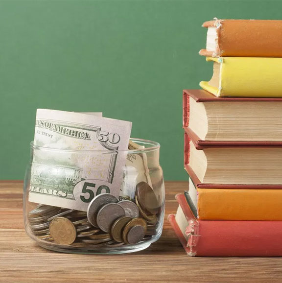 a glass jar with money inside of it next to a stack of books