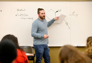 instructor writes notes about chemistry on whiteboard