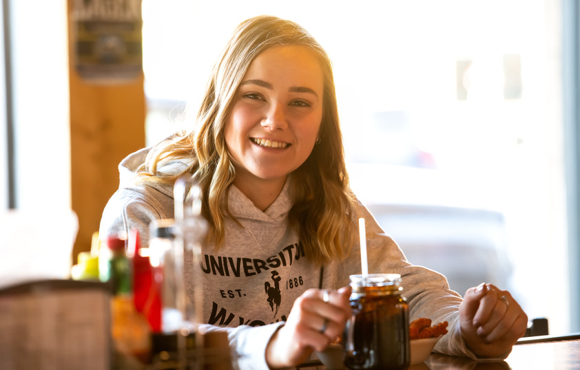 A student sit in a restaurant in Laramie smiling.