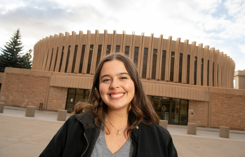 A student smiles in front of the UW classroom building