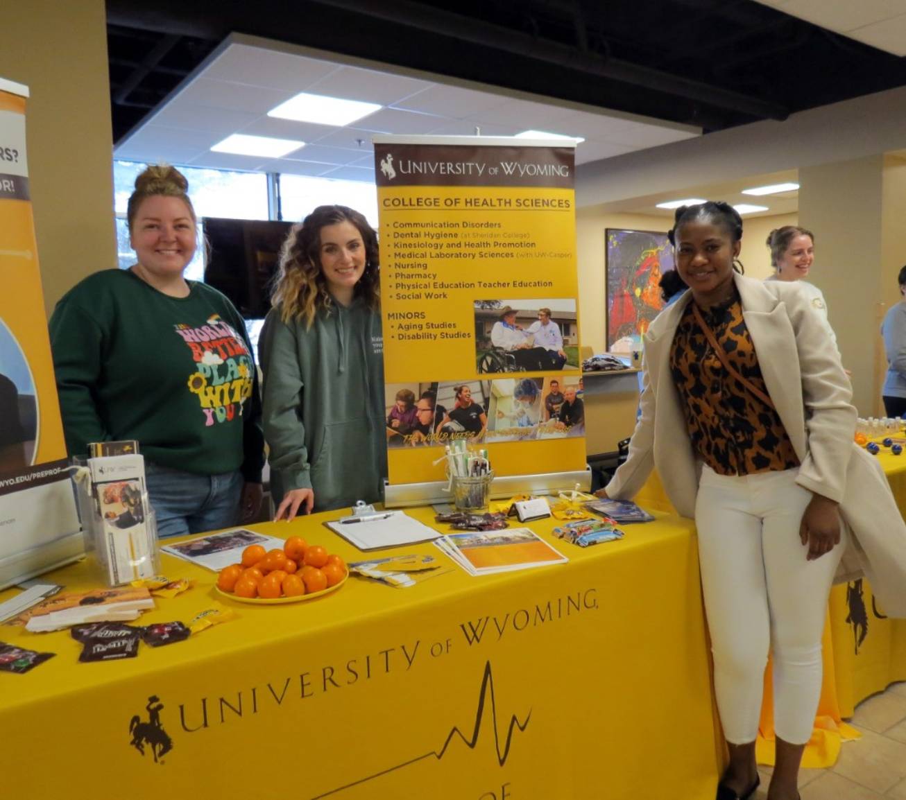 Three students smiling for picture at College of Health Sciences Union table