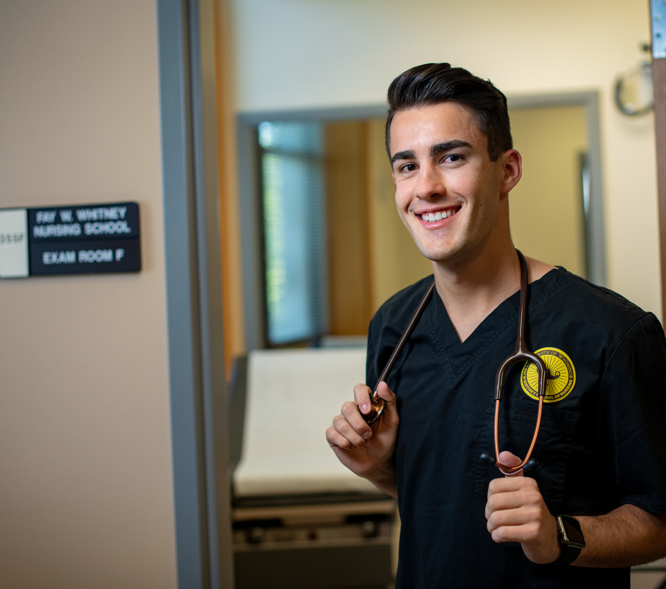 A student stands in the UW nursing building with their stethoscope. 