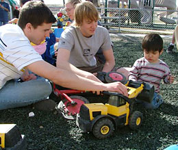 Two students and child play with toy truck