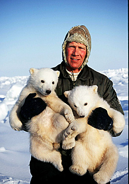 Man holding two polar bear cubs