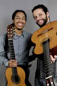 Two men holding guitars and smiling