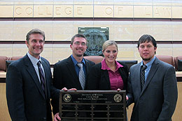 Four people holding plaque