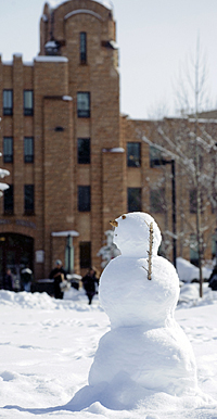 Snowman in front of stone building