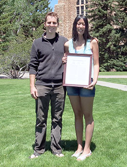 Two people holding framed paper