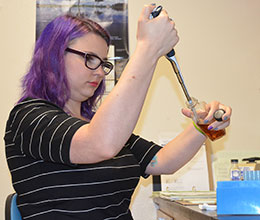 woman in lab using instrument with a bottle