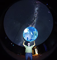 man lifting up arms to projected image of planet earth