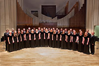 semi circle of people posed in front of pipe organ on stage