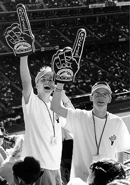 two young men waving foam fingers at baseball game