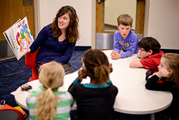 woman reading to a group of children at a table