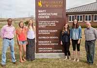 group of people standing beside a college building sign