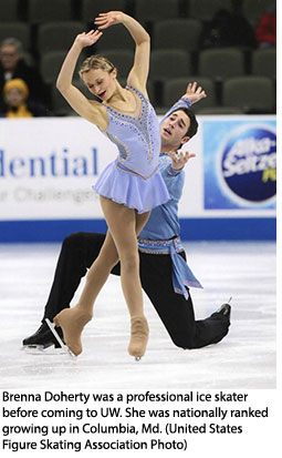 female figure skater on the ice, with a male skater crouched behind her