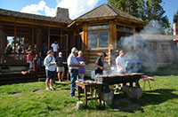 people outside a log building attending a barbecue